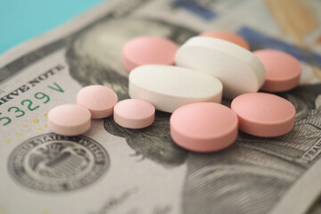 Various pills arranged on a hundred-dollar bill