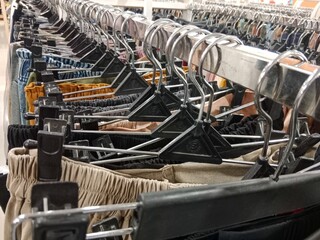 A row of colorful pants hanging on black plastic hangers in a clothing store