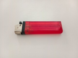 A red plastic gas lighter with a metal top, placed on a white surface