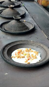 A man's hand makes surabi with oncom topping, a traditional pancake from West Java made from rice flour and coconut milk, cooked using a clay pan cooked using charcoal fire.
