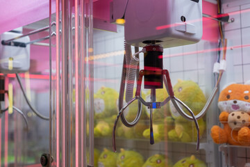 Claw machine close-up with plush toys inside, ready to be grabbed. The neon reflections and...