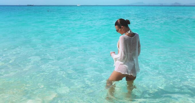 Elegant Woman In Sheer Cover-Up Walking Through Clear Blue Ocean