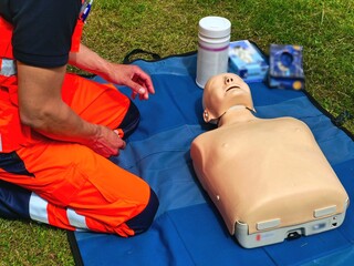 Paramedic Practicing CPR on Training Dummy Outdoors. Hands-On CPR Training on Dummy by Rescue...