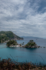 Idyllic view of Panagia Island with its small white chapel and lush greenery, located off the coast of Parga in the Ionian Sea. The scenic landscape combines turquoise water, dramatic cliffs