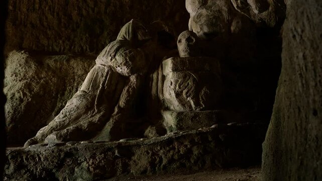 Stone statue of a praying monk with a skull in a cave in Pizzo, Calabria, Southern Italy