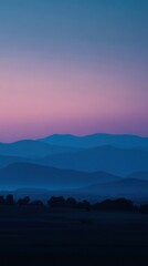 Obraz premium A serene landscape featuring layered blue mountains under a gradient pink and blue sky at dusk or dawn