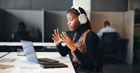 Headphones, laptop and video call with business black woman in office for learning online. Computer, streaming and virtual meeting with employee listening to training course for upskill development © FantiS/peopleimages.com