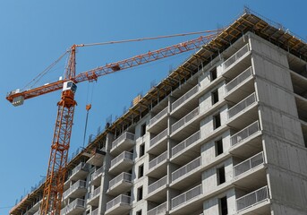 Construction of a modern residential building with a crane against a blue sky