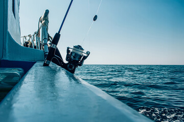 Naklejka premium Fishing rod on a boat cruising through the open sea on a clear day