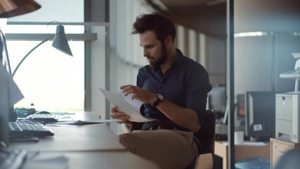 Serious businessman reading documents at modern office desk  - Powered by Adobe