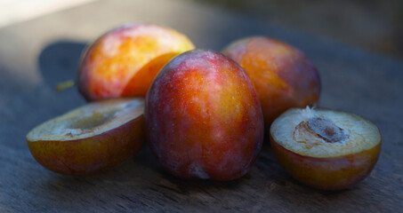 Cut and whole plums on a board in nature