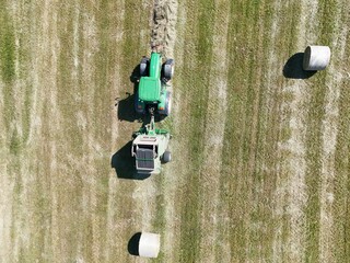 A tractor with a baler in the field, shot with a drone