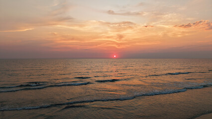 Gentle waves rolling onto the shore during a vibrant sunset, creating a tranquil and picturesque scene, perfect for representing peace, relaxation, and the beauty of nature