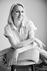 Pretty female relaxing on bar stool. Portrait of woman with blonde hair smiling straight to camera....