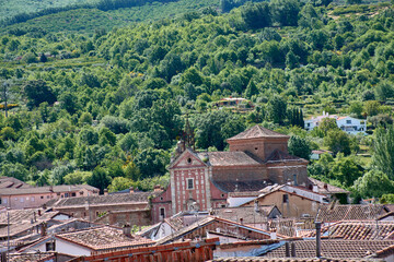 The Church of San Juan Bautista in Hervas, Extremadura, with its rooftops and bell tower, framed by...