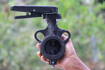 Butterfly valve made with cast metal used to control flow of fluids held in the hand on nature...
