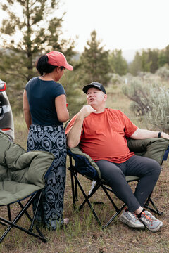 Interracial couple talking at campsite in forested outdoor setting