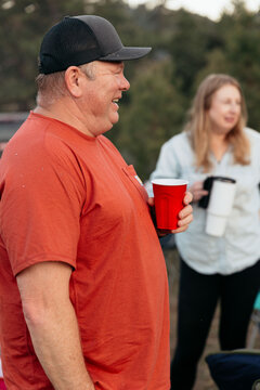 Man wearing baseball cap holding red plastic cup and smiling