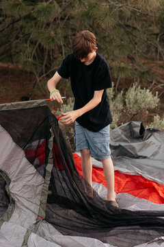 Boy setting up tent while camping in nature