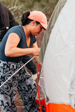 Thai woman putting tent poles into a tent at campsite