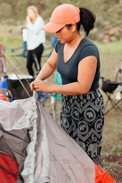 Woman setting up tent at campsite on a sunny day