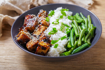 plate of fried tofu with sesame seeds, rice and green beans