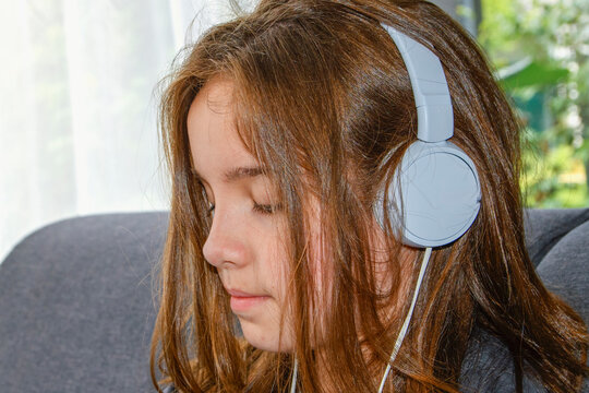 Teenage girl with headphones at home close-up, 10-12 years old