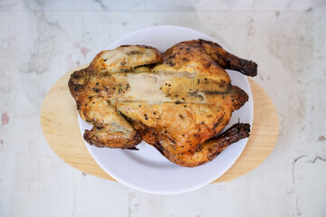 Roasted chicken whole on white plate	
