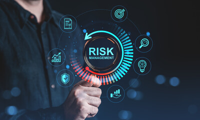 Businessman holding magnifying glass focused on digital risk management interface with icons...