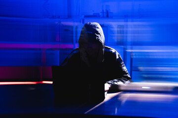 Darkened Figure Engaged in Coding and Security Behind Laptop