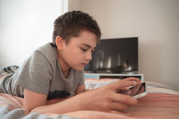 Fototapeta premium Kid Online Education,Asian Child using tablet computer Ai technology for homework,Schoolboy watching online movie, cartoon,playing virtual in bed,Concept Kid and digital technology addiction