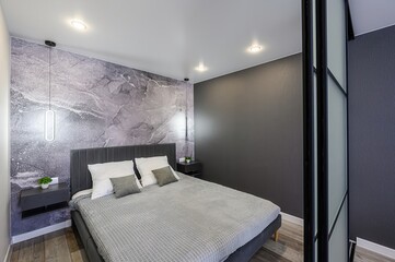 modern bedroom featuring a gray bed with white and gray pillows, gray walls, marble wallpaper,...