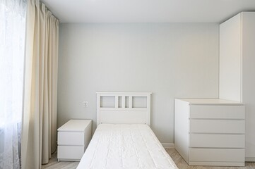 minimalist bedroom with a white bed, dresser, nightstand, and light curtains. Clean, simple design