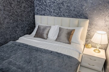 cozy bedroom features a well-made bed with a plush gray blanket, soft pillows, and a nightstand...