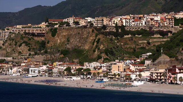 Panoramic view of Scilla, Calabria, with colorful buildings on a cliff overlooking the beach and the Tyrrhenian Sea, a popular tourist destination in Italy