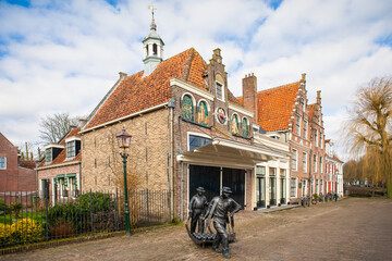 The Kaasmarkt Edam (Edam Cheese Market) building at the town of Edam in Netherlands on a bright winter morning, featuring a bronze statue of cheese carriers
