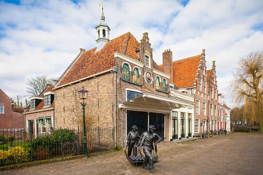 The Kaasmarkt Edam (Edam Cheese Market) building at the town of Edam in Netherlands on a bright winter morning, featuring a bronze statue of cheese carriers
