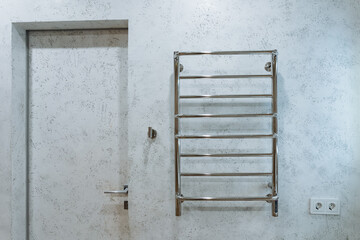 A towel rack is securely hanging on the wall right next to an entrance door, providing easy access for towels in a convenient location for individuals entering or exiting the room