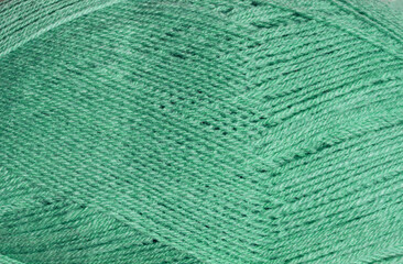 The texture of the green wool ball shows the tightly twisted threads.