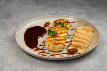 Cottage cheese pancakes with caramel sauce on a plate with chocolate and nut spread on a gray background. Concept of a nutritious and healthy breakfast. Top view, copy space.
