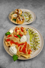 Exquisite dinner or lunch. Two plates with dishes made from thin pancakes and stuffed with red caviar, mushrooms. Preparation and serving of dishes in restaurants.