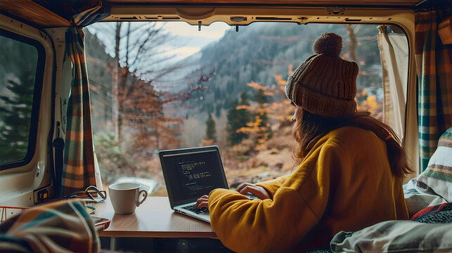 Woman working on laptop in cozy camper with open back door, scenic mountains, forest view outside, cup of coffee on the side, warm morning light, boho travel style. Freelancer, remote work - Powered by Adobe