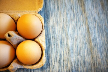 Brown chicken eggs in paper box with blue background.