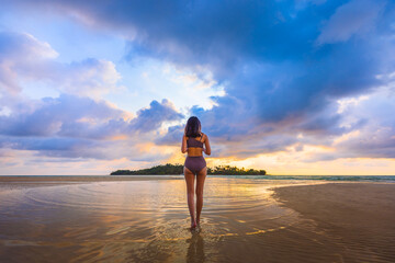 Happy traveler asian woman with bikini relax on sea Klong Rahan beach in sunset at Koh Kood Trat...