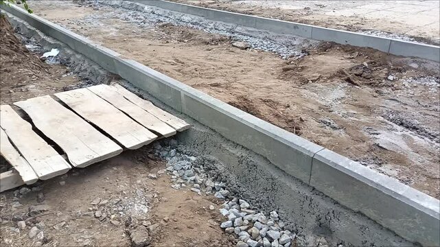 The curb slabs are filled with concrete. Construction of a sidewalk road.