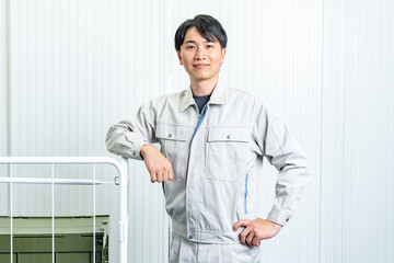 倉庫内で仕事をするカメラ目線の作業着を着た男性