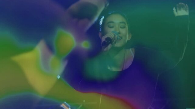 Female singer stepping into spotlight on music stage singing into microphone in haze engaging crowd