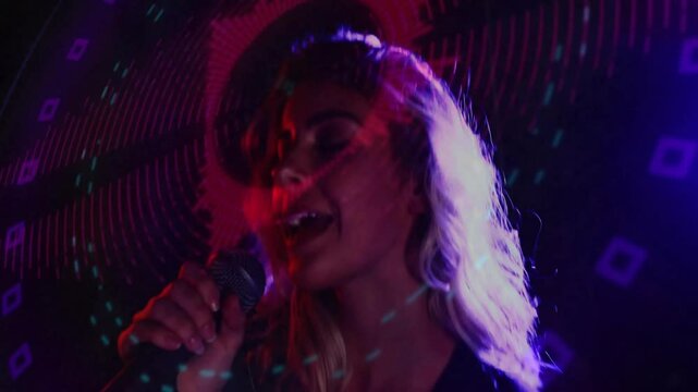 Singer lifting microphone from below and activating neon spiral projections for music performance