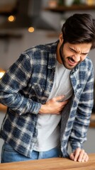 Obraz premium Man in plaid shirt clutches stomach experiencing pain