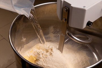 Pouring water into the dough mixer.